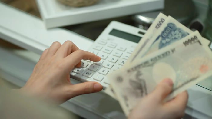 mano sujetando billetes y mano sujetando calculadora