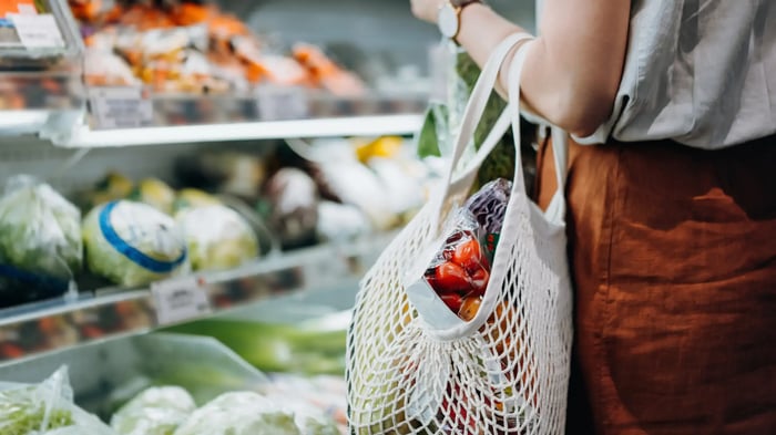 mujer con una bolsa de compra de rejilla en un supermercado