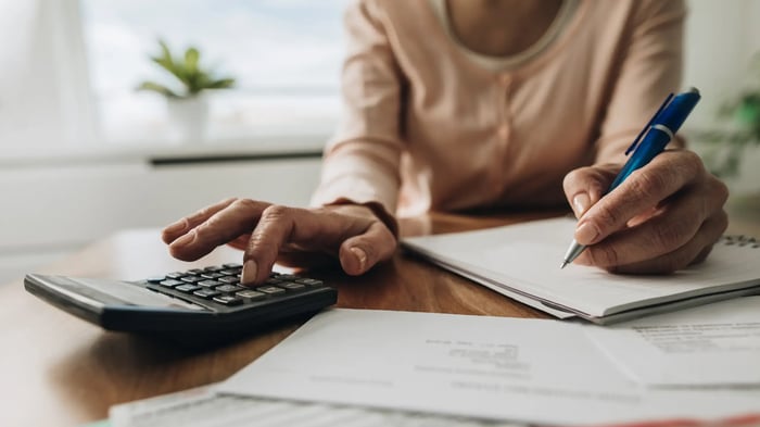 manos de mujer de color con calculadora y bolígrafo realizando cálculos