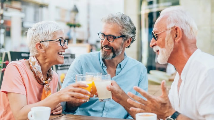 Tres personas mayores brindando en una terraza