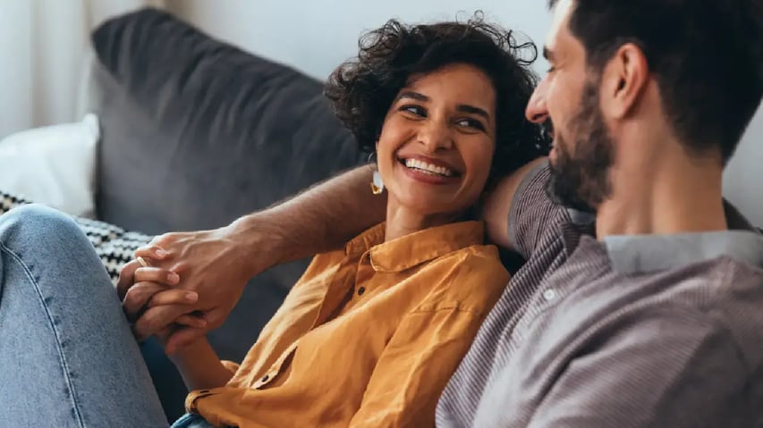 un hombre y una mujer sentados en un sofá sonriendo