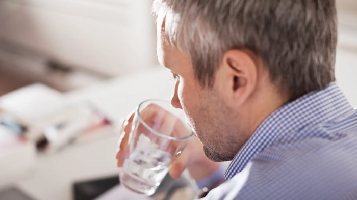 hombre canoso pensativo bebiendo en un vaso con hielos