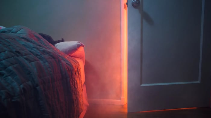 persona durmiendo en la cama con la puerta entre abierta y se ve humo de que hay fuego