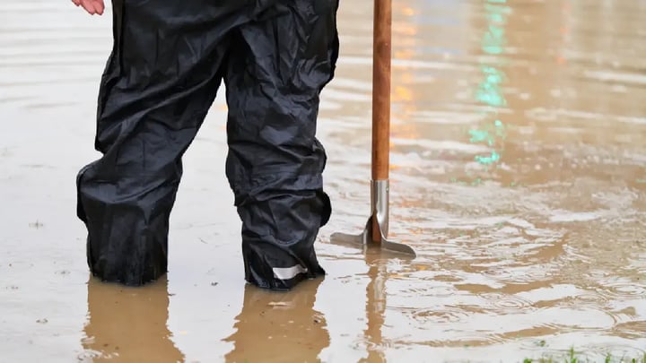 hombre cubierto de agua hasta las rodillas con una pala
