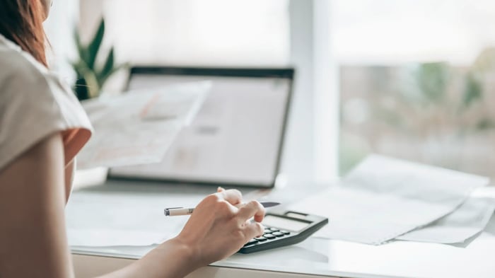 mujer con una calculadora y un bolígrafo en la mano en una mesa de escritorio