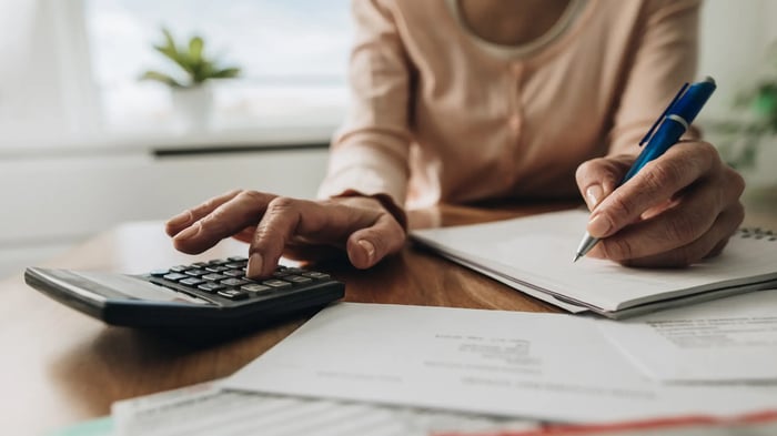 mujer de color en un escritorio con una calculadora, bolígrafo y papeles