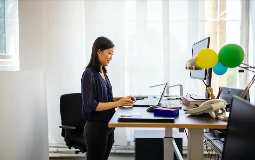 mujer-trabajando-en-un-escritorio-ergonomico-de-pie-mientras-realiza-una-teleconferencia