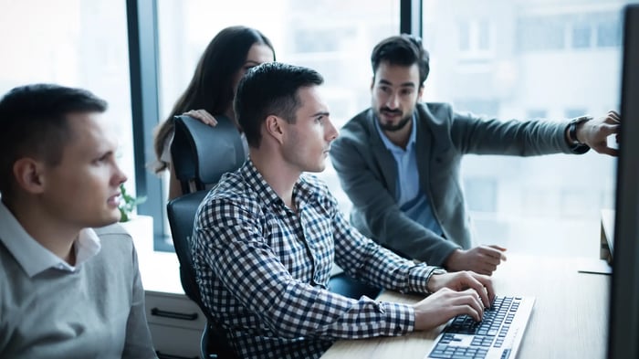 personas reunidas delante de un ordenador